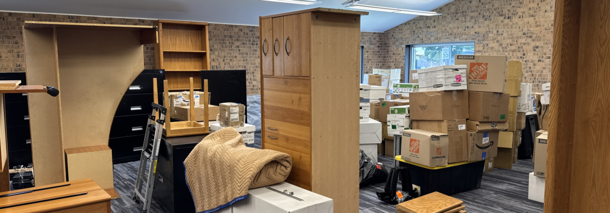Office space filled with packed boxes and disassembled furniture during a relocation.