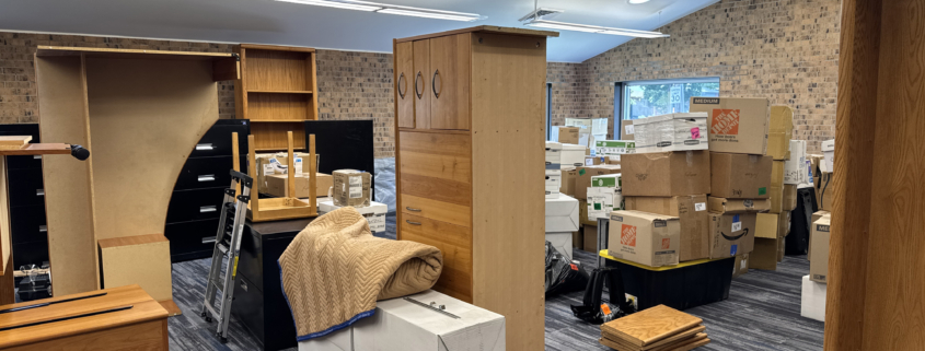 Office space filled with packed boxes and disassembled furniture during a relocation.